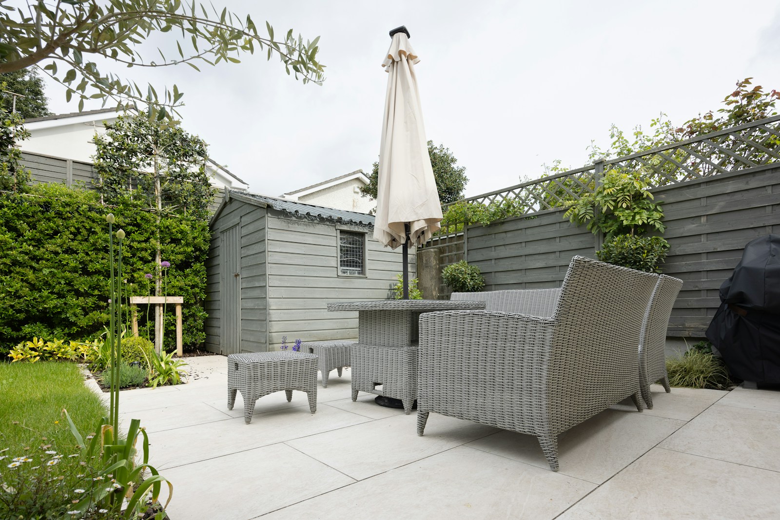 Clean stone patio with garden seating and painted timber fencing